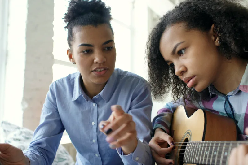 A guitar and sheet music in a practice room.